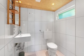 Et badeværelse med hvid vask, toilet og træloft.