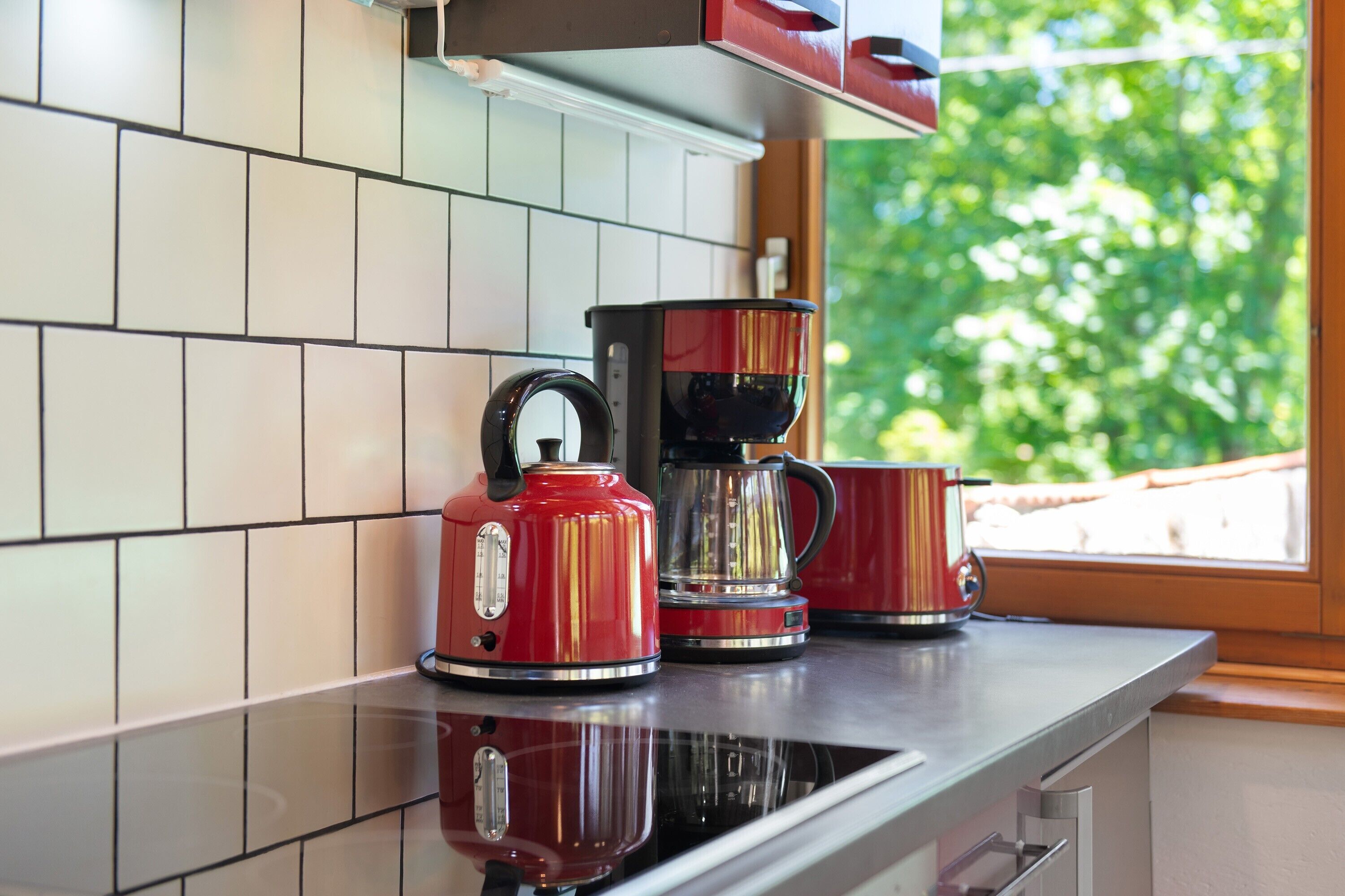 Een keuken met een koffiezetapparaat, een waterkoker en een mok op een aanrecht.