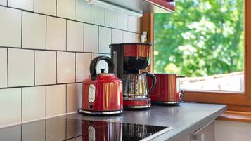Een keuken met een koffiezetapparaat, een waterkoker en een mok op een aanrecht.