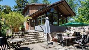 Eine Holzhütte mit Steinwand, Sitzgelegenheiten im Freien und einer überdachten Terrasse.