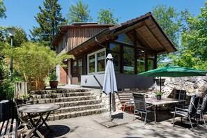 En træhytte med en stenvæg, udendørs møbler og en overdækket terrasse.