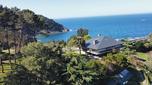 Une propriété située sur la côte, dotée d’une grande maison, offrant une vue sur l’océan et entourée de verdure.