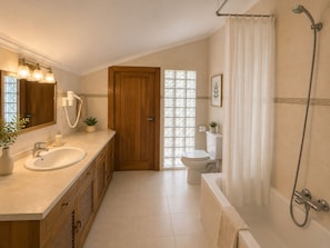 A modern bathroom with a sink, mirror, shower, and toilet. - Hotel Arresi (Lemoiz)
