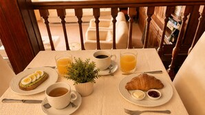 Una mesa de desayuno con croissants, huevos, café y jugo.