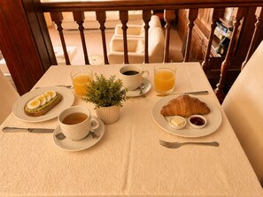 Una mesa de desayuno con croissants, huevos, café y jugo.