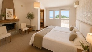 Une chambre dotée d’une cheminée, de deux lits, d’un coin salon et offrant une vue sur l’extérieur.