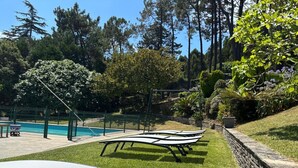 Zona de piscina con sillones de descanso y un muro de piedra.