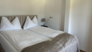 A double bed with white linens, a bedside table with a lamp, and a neutral-colored headboard. - FarawayHomes Studio Leoben #P72 (Donawitz)