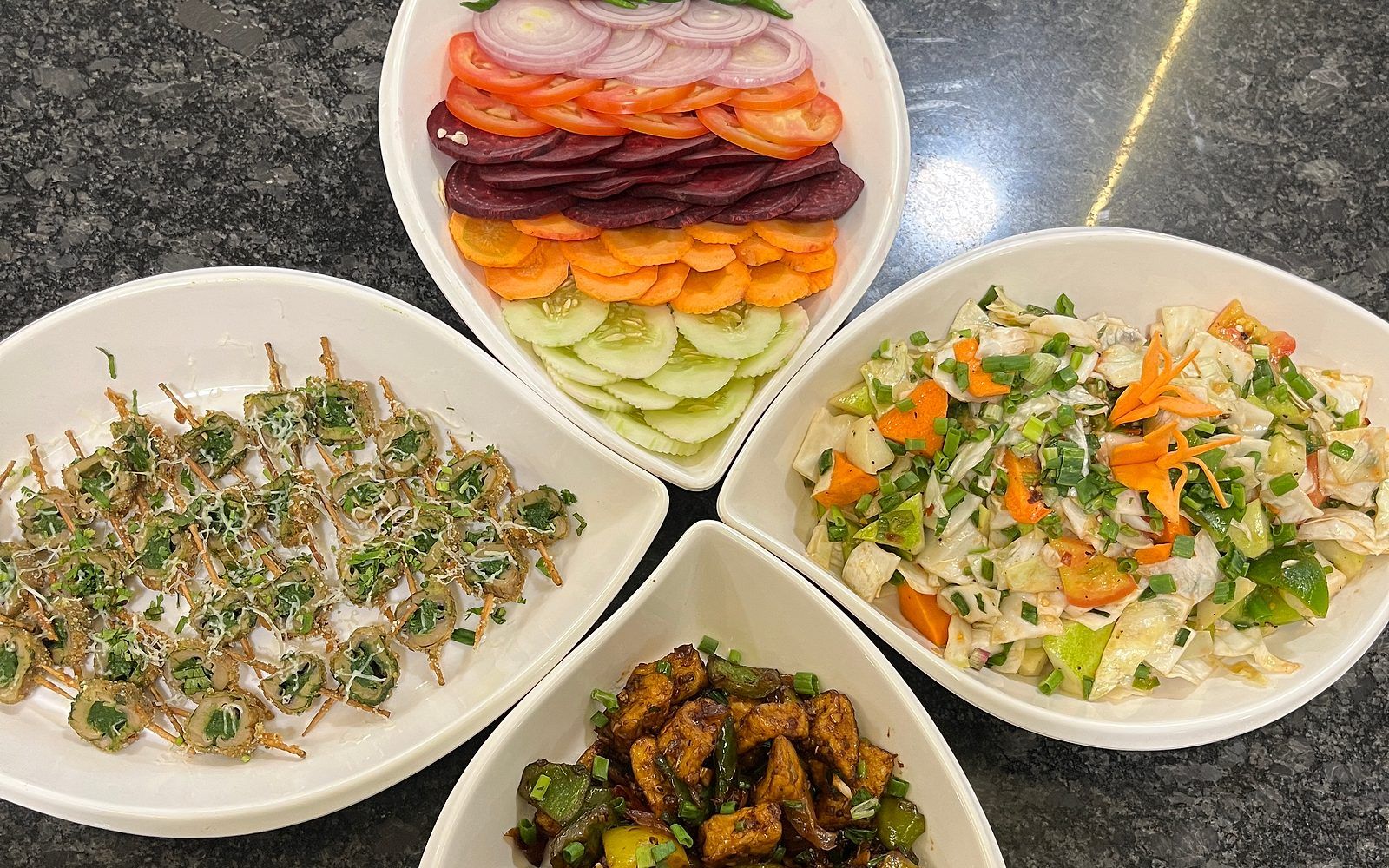 Quatre bols contenant différents types de légumes et un plat avec des aliments frits.