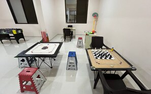 A room with a foosball table, a table tennis table, and a chess table. - The Purple Mango - Pure Veg (Lonavala)