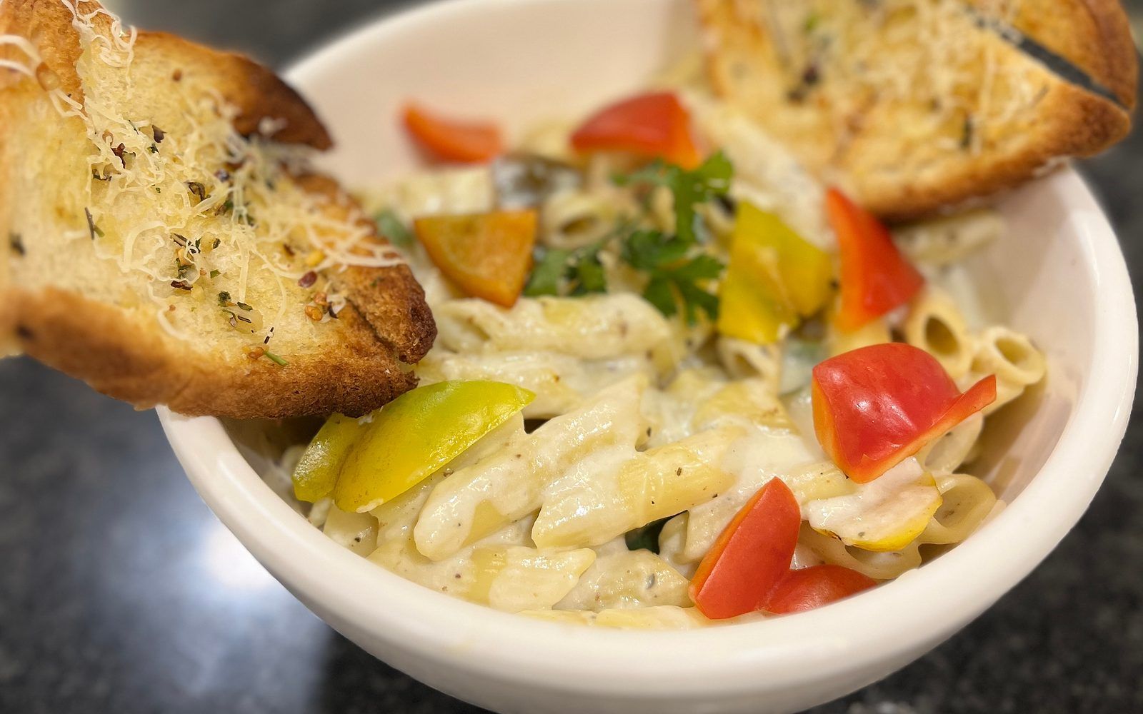 A bowl of pasta with vegetables and bread.