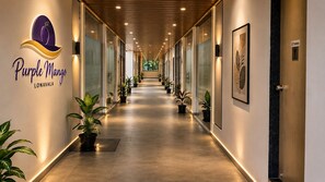 A hotel corridor with a sign for 'Purple Mango Lonavala,' potted plants, and a sign indicating toilets. - The Purple Mango - Pure Veg (Lonavala)