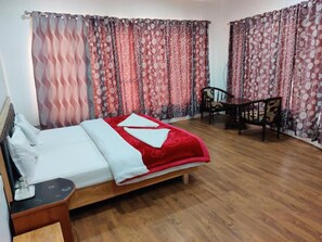 A room with a bed, a chair, a small table, and curtains. - Goji Villa (Leh)