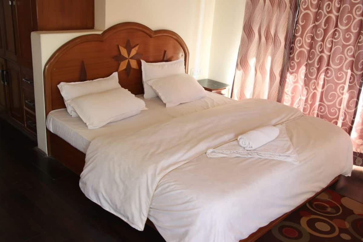 A neatly made bed with a wooden headboard, white bedding, and a folded towel on the bed.