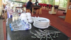 Disposición de un bufé con platos apilados, tenedores y botellas de agua.