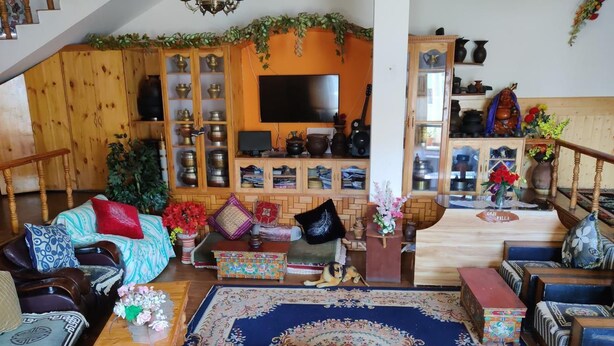 Una sala de estar acogedora con televisor, muebles de madera y un tapete grande.