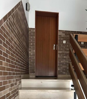 A staircase with a wooden door, brick walls, and a metal railing. - Quiet 1-Bedroom Apartment · Sleeps 2 · Full Kitchen · Kaiserslautern (Kaiserslautern)