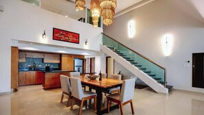 Amplia sala de estar con mesa de comedor, sillas, cocina y escalera.