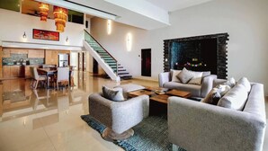 Una sala moderna con sofá, mesa de centro y chimenea. Una escalera conduce a un nivel superior.