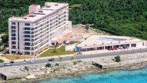 Un hotel de varios pisos con techo plano, piscina y estacionamiento.