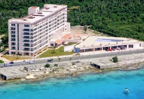 A multi-story hotel with a flat roof, a swimming pool, and a parking area. - Incredible! Spacious Apartment Just Steps From the sea (Cozumel)