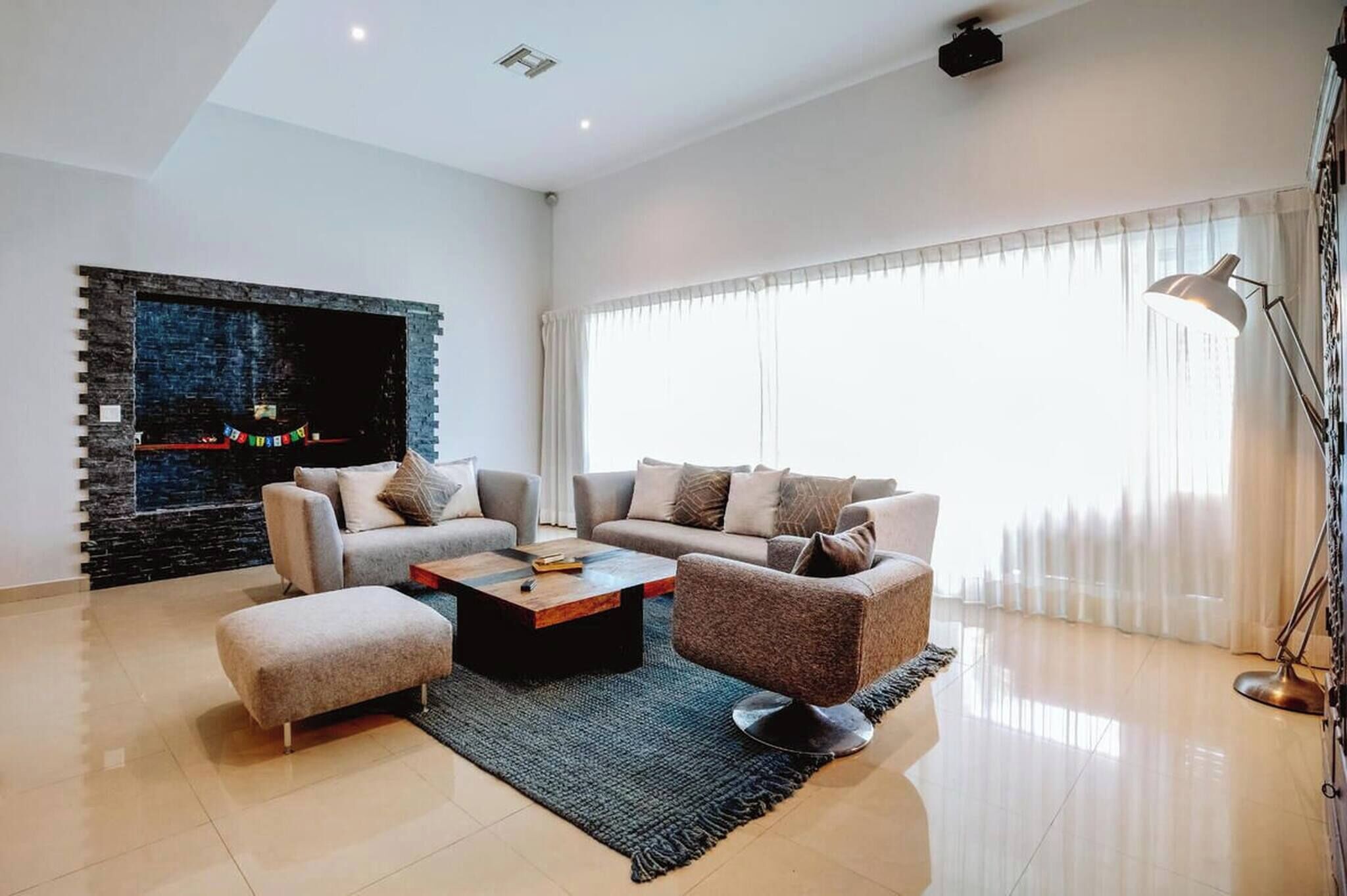 A modern living room with a sectional sofa, a coffee table, and a flat-screen TV mounted on a stone wall.