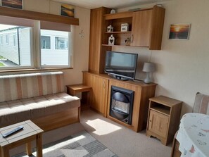 Ein gemütlicher Wohnbereich mit einer Couch, einem Fernseher, einem kleinen Schrank und einem Heizgerät.