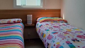 A room with two beds, a window with a view of a building, and a curtain. - Ty Mawr Holiday Park - Holiday Accommodation 21752 (Abergele)