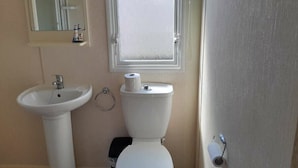 A bathroom with a sink, toilet, and a window above the toilet. - Ty Mawr Holiday Park - Holiday Accommodation 21752 (Abergele)