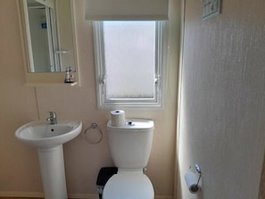 Ein Badezimmer mit Waschbecken, Toilette und einem Fenster über der Toilette.