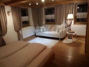 Un dormitorio con cama, sofá, lámpara y ventana con cortinas.