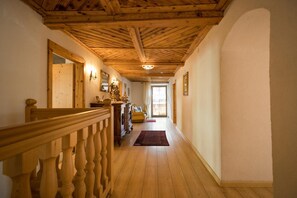 Ein hölzerner Gang mit Treppe, einer Holztür und einem Fenster am Ende.