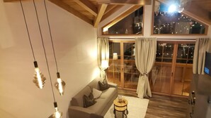 Ein modernes Wohnzimmer mit einer Couch, einem Holztisch und hängenden Pendelleuchten.