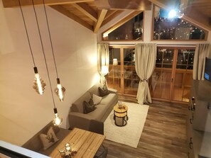 Uma sala de estar moderna com um sofá, uma mesa de centro de madeira e luminárias pendentes.