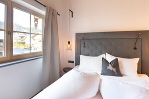Ein Hotelzimmer mit Bett, einem Fenster mit Vorhängen, einem Nachttisch und einer Wandleuchte.