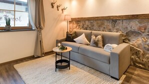 En hyggelig stue med sofa, lille sofabord, lampe og stenvæg.
