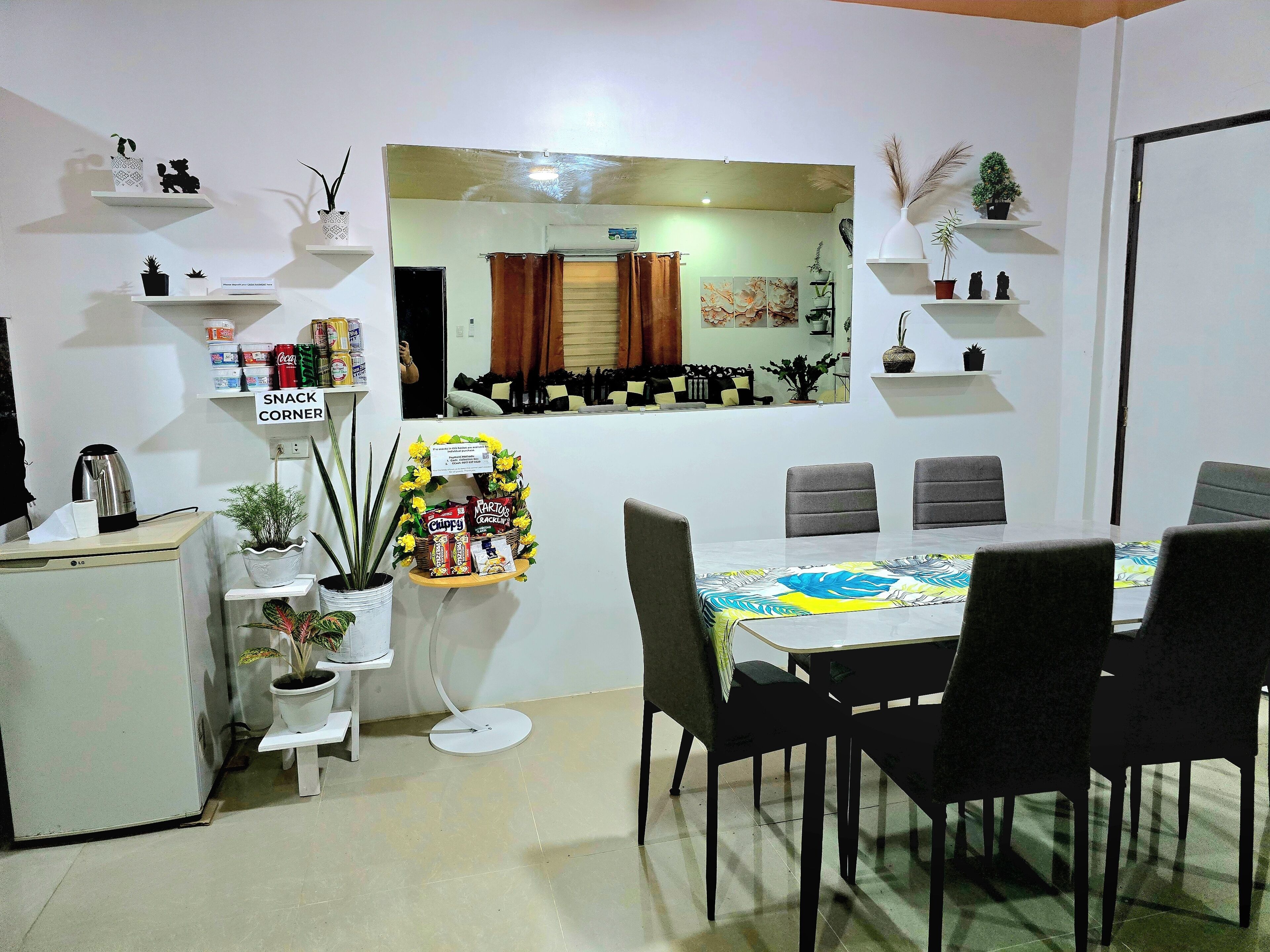 A dining area with a table, chairs, a coffee machine, and snack shelves.