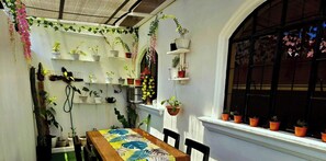 A room with a dining table, chairs, potted plants, and a window with a view. - Cozy 3-BR house. 15 pax.  Fast WIFI. Near Iloilo airport.  Pet friendly (Zarraga)