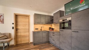 Eine moderne Küche mit grauen Schränken, einer Holztür und einem Schild mit der Aufschrift 'Das Krumerhaus'.