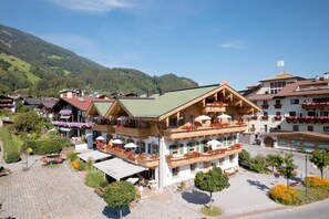 A traditional chalet-style hotel with balconies, a paved courtyard, and a mountainous backdrop. - Apartment "Das Krumerhaus – Die Krumerlodge" with Mountain View, Balcony and Wi-Fi (Aschau im Zillertal)