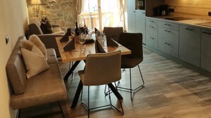 Eine moderne Küche mit Holzausstattung, ein Essbereich mit Holztisch und -stühlen sowie eine Steinwand.
