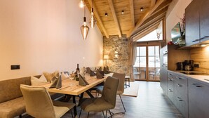 Eine moderne Küche mit Holzbalken, einer Steinwand und einem Essbereich mit Holztisch und Stühlen.
