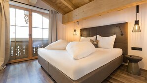 Ein Schlafzimmer mit einem großen Bett, Holzbalkendecke, einer Schiebetür und einem Nachttisch mit Lampe.