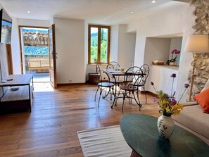Una habitación amplia con una mesa de comedor, sillas, un sofá y un jarrón de flores.