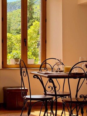 Un comedor con mesa y sillas, una ventana que da a zonas verdes y un taburete pequeño.