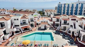 A resort with a central swimming pool, multiple balconies, and a view of the sea. - Apartment with terrace and pool, Los Cristianos. (Los Cristianos)