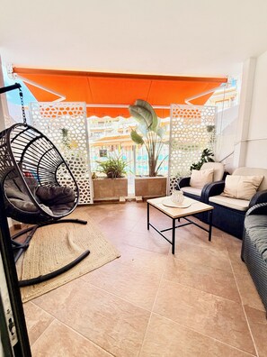 A cozy patio with a swing chair, a cushioned sofa, and a table with a decorative item. - Apartment with terrace and pool, Los Cristianos. (Los Cristianos)
