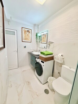 A compact bathroom with a washing machine, toilet, and a small sink area. - Apartment with terrace and pool, Los Cristianos. (Los Cristianos)