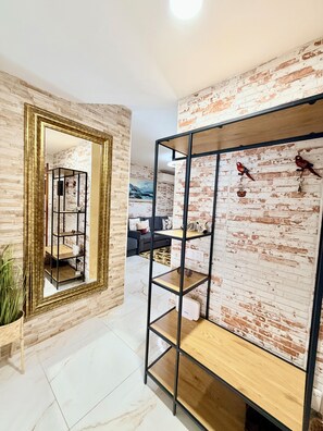 Ein modernes Interieur mit einer Ziegelwand, einem beschlagenen Kleiderschrank und einem schwarzen Metallregal.