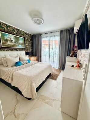 A bedroom with a bed, a nightstand, a dresser, a window with curtains, and a mounted air conditioner. - Apartment with terrace and pool, Los Cristianos. (Los Cristianos)